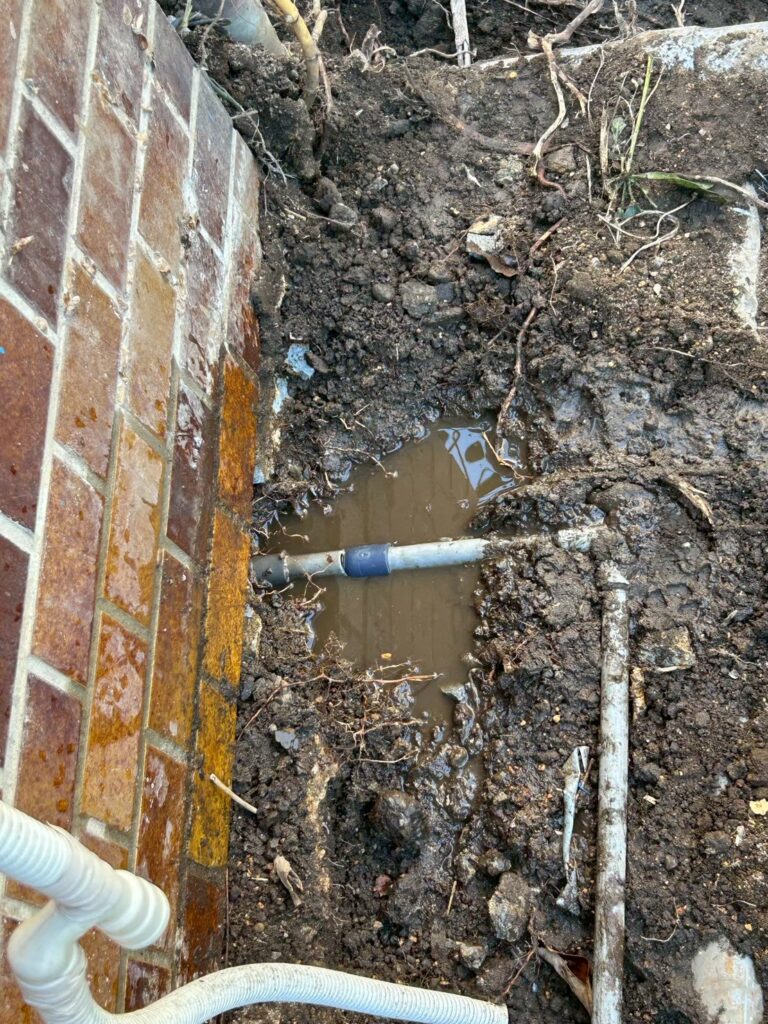 地面を掘って水道管が見える状態になった様子。掘った穴の中に水がたまっているのがわかる